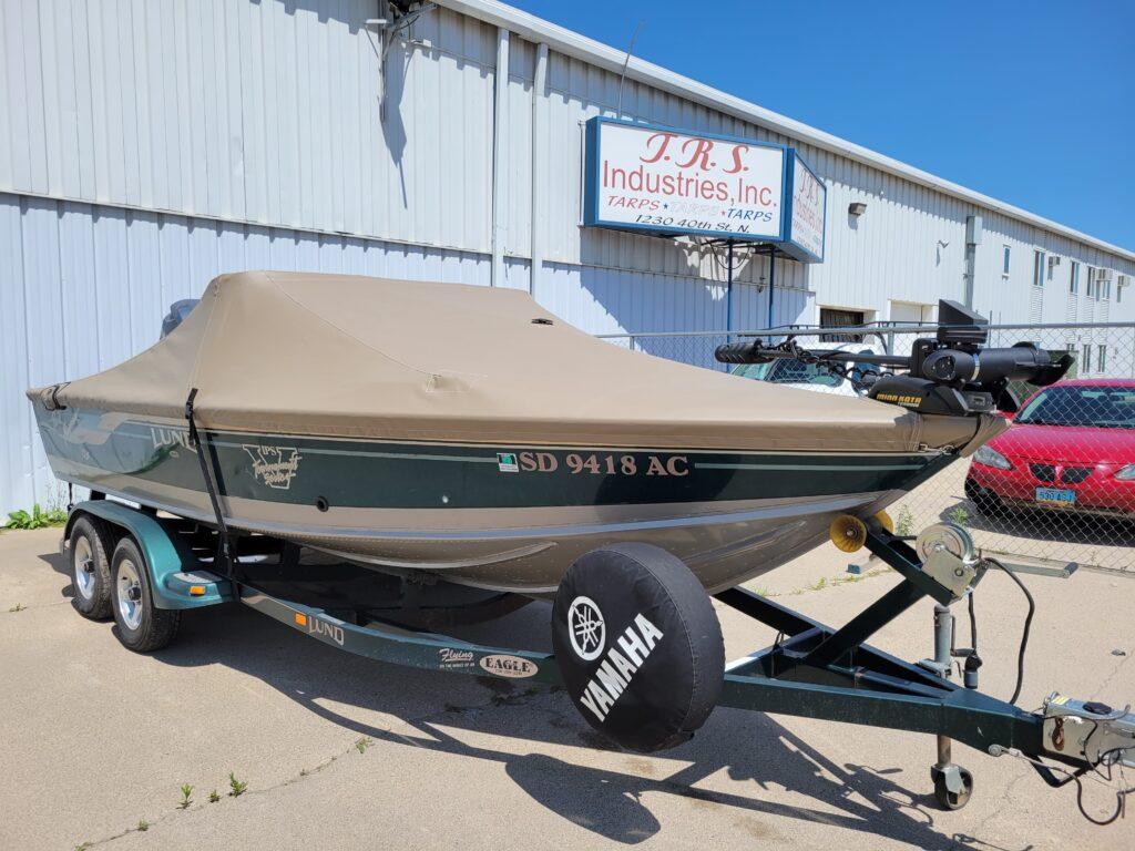 Green Lund boat with tan cover in front of T.R.S. Industries.