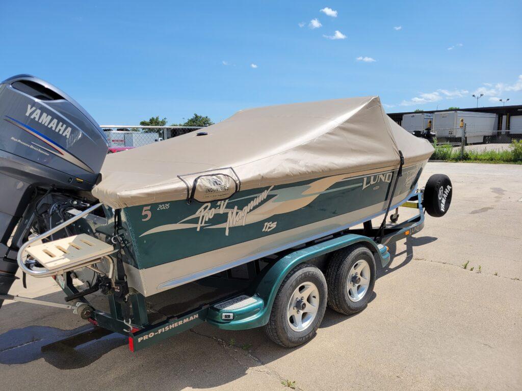 Green Lund boat with tan cover in front of T.R.S. Industries.