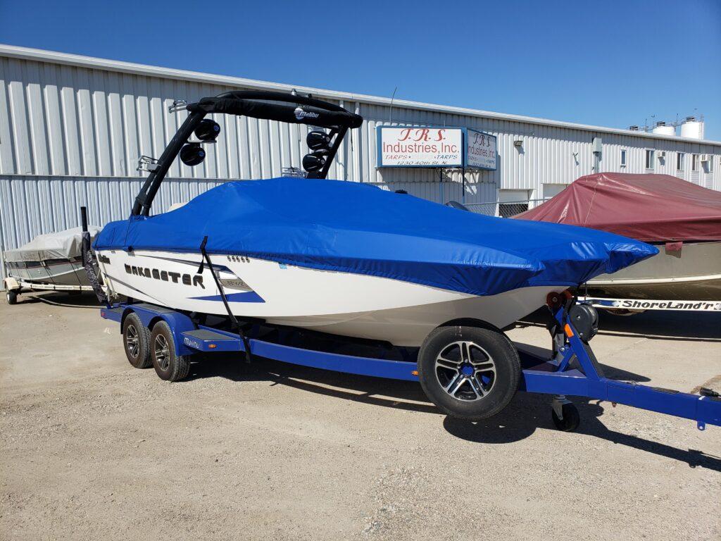 White boat with blue cover in front of T.R.S. Industries.