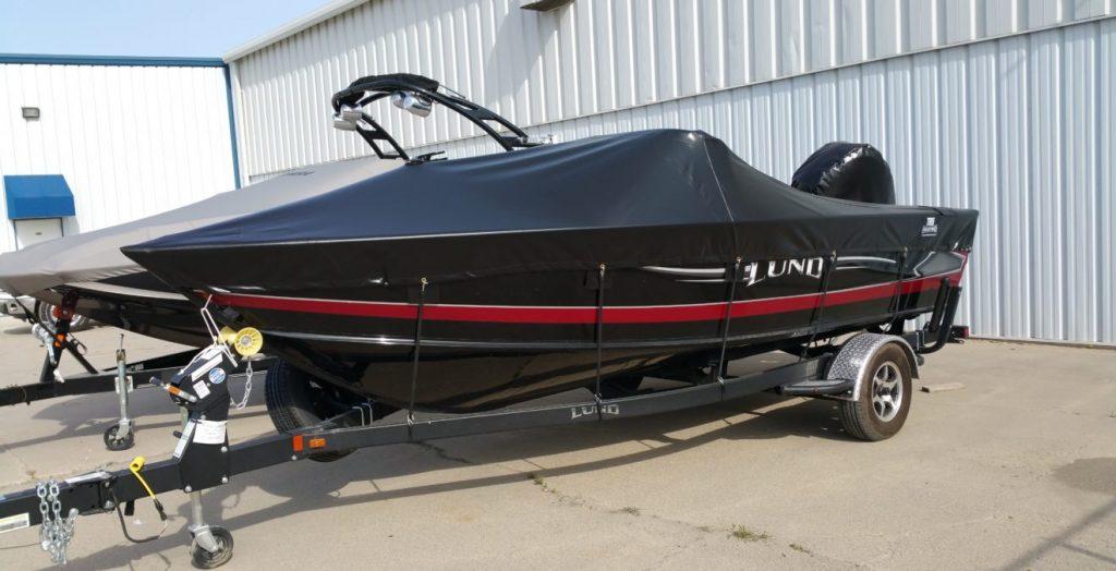 Lund boat with black cover in front of T.R.S. Industries.