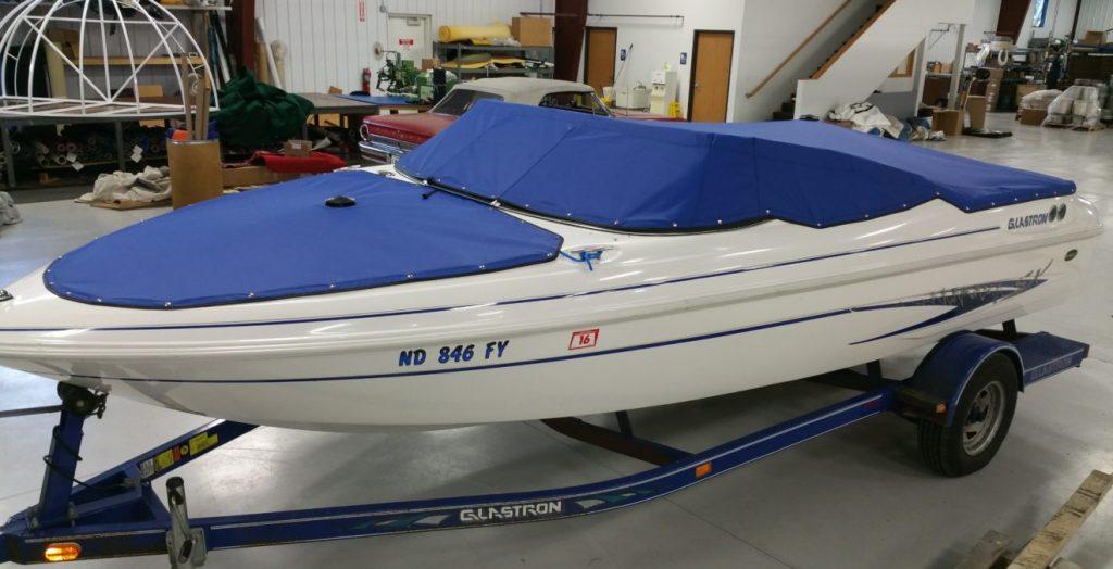 White Glastron boat with blue cover.