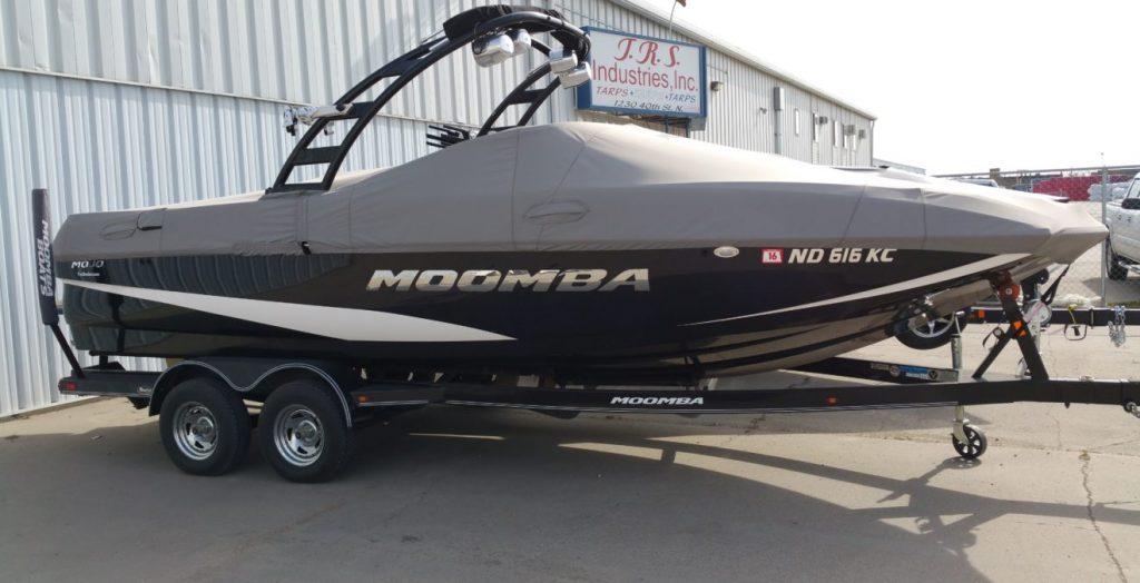 Moomba boat with gray cover in front of T.R.S. Industries.