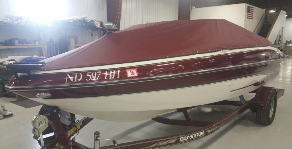 Glastron boat with maroon cover.