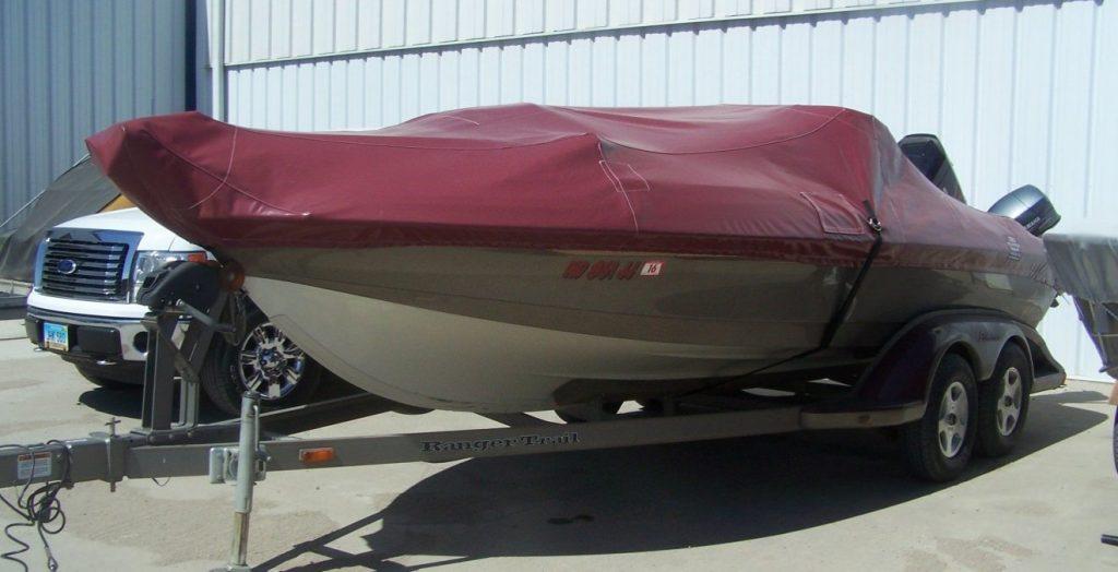 Boat with a maroon cover in front of T.R.S. Industries.