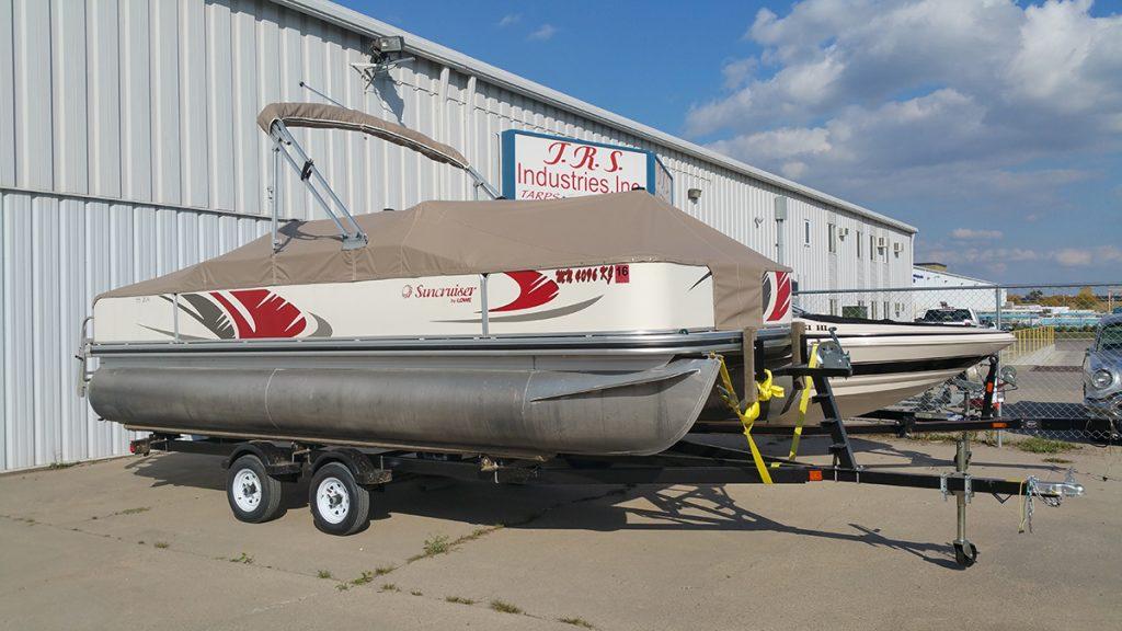 Suncruiser pontoon with tan cover in front of T.R.S. Industries.