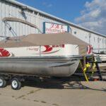 Suncruiser pontoon with brown cover in front of T.R.S. Industries.