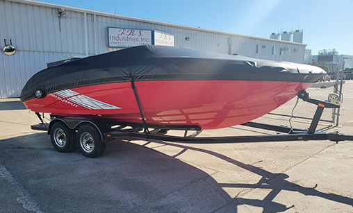TRS_Industries_Boat_and_Marine_Service Red and black speed boat on a trailer, fitted with a custom black boat cover outdoors.
