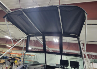 Custom black canvas boat enclosure top fitted over a windshield and frame.
