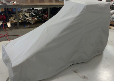 Full-length custom light grey protective cover fitted completely over a vehicle or machinery.