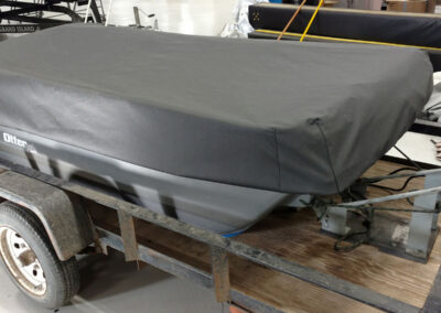Fitted black heavy-duty cover secured snugly over a utility trailer bed.