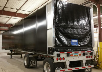 Accordion-style retractable Conestoga tarp system on a flatbed trailer