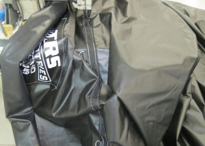 Close-up of heavy-duty black tarp material showing double-stitched reinforced seams and brand labeling.