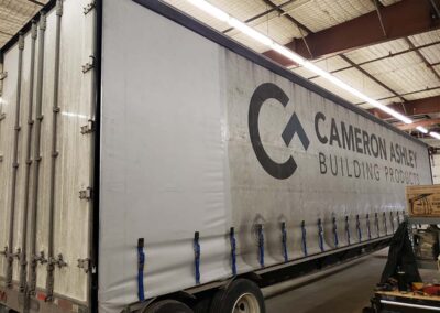 A light orange custom-fitted cover protecting a sleek powerboat on a trailer.