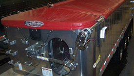 agricultural-farm-grain-trailer-tarp A close-up view of a custom, heavy-duty red tarp installed tightly on a metallic agricultural grain trailer.
