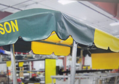 Close-up showroom shot of a dark green boat lift canopy featuring custom yellow text reading "BISON" on the front valance panel.