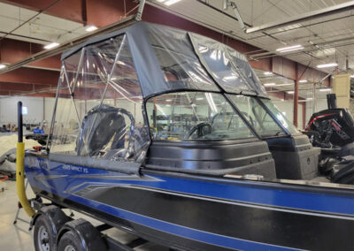 Close-up view of a vibrant blue canvas boat bimini top with zippered clear vinyl front and side curtains.