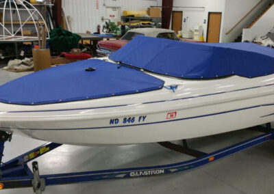Side-profile view of a trailered white boat featuring a matching vibrant blue snap-on cockpit cover and separate bow canvas.