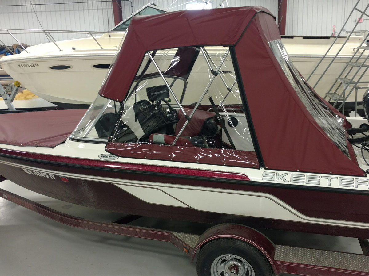 burgundy-bimini-top-with-clear-windshield Side view of a burgundy marine canvas bimini top integrated with a clear vinyl front windshield panel.
