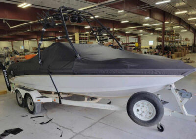 Close-up side view of a boat on a trailer utilizing a secure charcoal gray marine-grade mooring cover.
