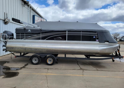 Charcoal gray full mooring cover fitted over a pontoon boat on a trailer.