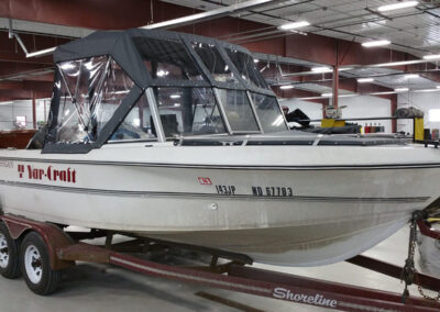 Angled front-facing view of a boat equipped with a charcoal gray canvas bimini top and integrated storage boot.