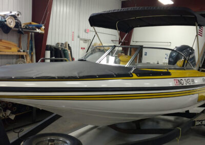 Side-profile view of a mid-sized boat featuring a complete marine canvas camper top with clear windows.