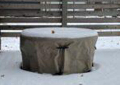 Protective fitted cover installed over an outdoor fire pit