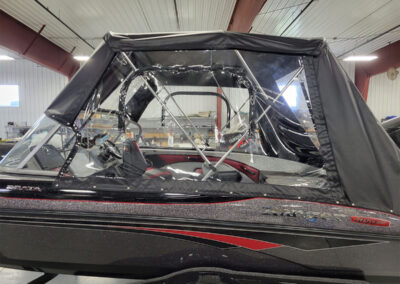 Side view of a boat completely enclosed with a gray marine canvas cover and structured clear framing panels.