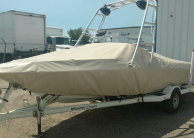 Profile view of a trailered boat fully protected under a sleek, tightly secured dark gray custom canvas cover.