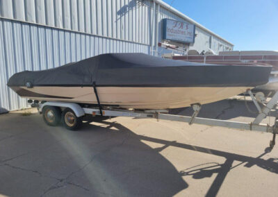 Wide side view of a premium cream and dark gray boat utilizing a tightly adjusted dark gray custom ratchet cover.