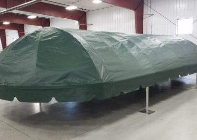 Full warehouse floor view of a structured dark green replacement vinyl skin stretched perfectly across a boat lift top frame.