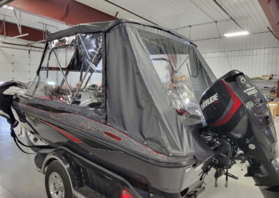 Side-angle view of a complete custom gray marine canvas enclosure with clear window panels on a boat.