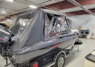 Exterior view of a boat's custom gray bimini top with zippered clear vinyl front panels attached.