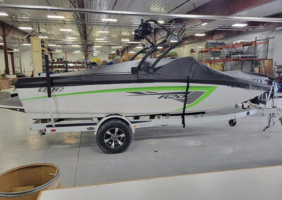 Side view of a boat on a trailer outfitted with a custom gray marine cover fitted around a wakeboard tower.