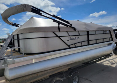 Gray pontoon boat mooring cover fitted around the deck railings.
