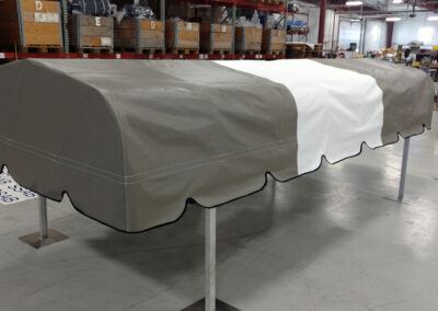 Warehouse display shot of a custom boat lift canopy assembled using alternating gray and white vinyl panels.