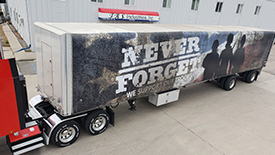 industrial-commercial-semi-trailer-tarp A white semi-truck trailer featuring a custom graphic: "NEVER FORGET" and an image of soldiers.