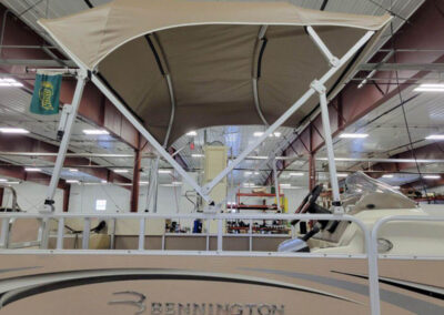 Open tan bimini top canopy extended over the seating area of a Bennington pontoon boat.