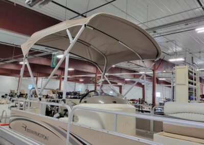 Tan bimini top canopy expanded over pontoon boat interior seating.