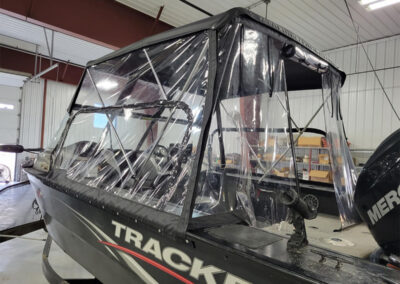 Front view of a boat outfitted with a custom maroon or burgundy canvas bimini top enclosure.