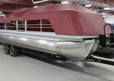 Maroon playpen cover fitted over the railing of a pontoon boat.