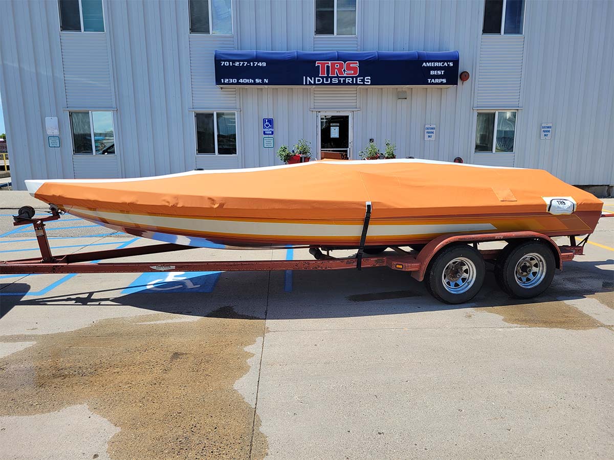 orange-custom-boat-cover A light orange custom-fitted cover protecting a sleek powerboat on a trailer.