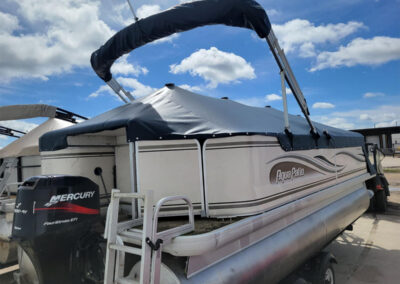 Dark blue bimini top and matching mooring cover on a pontoon boat.