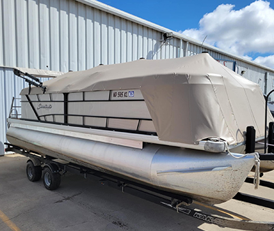 pontoon-boat-marine-canvas-services A custom pontoon boat enclosure made of canvas and clear windows, fully enveloping the boat on a trailer.