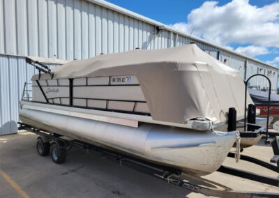 Full tan playpen pontoon boat cover secured over the entire top deck.