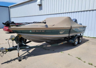 Clean side profile shot of a flat-bottomed boat hull sealed under a tight, form-fitting tan custom ratchet cover.