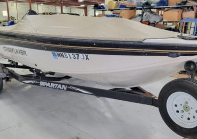Side profile shot of a boat on a single-axle trailer utilizing a tightly snapped tan custom cockpit and bow cover set.