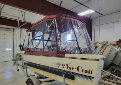 Wide angle view of a dark gray canvas bimini top and full clear enclosure on a Track boat.