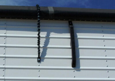 Tarp tamer accessory attached to a trailer tarp system