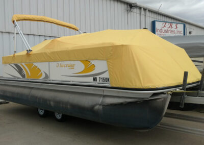Bright yellow custom boat cover fitted over a pontoon boat on a trailer.